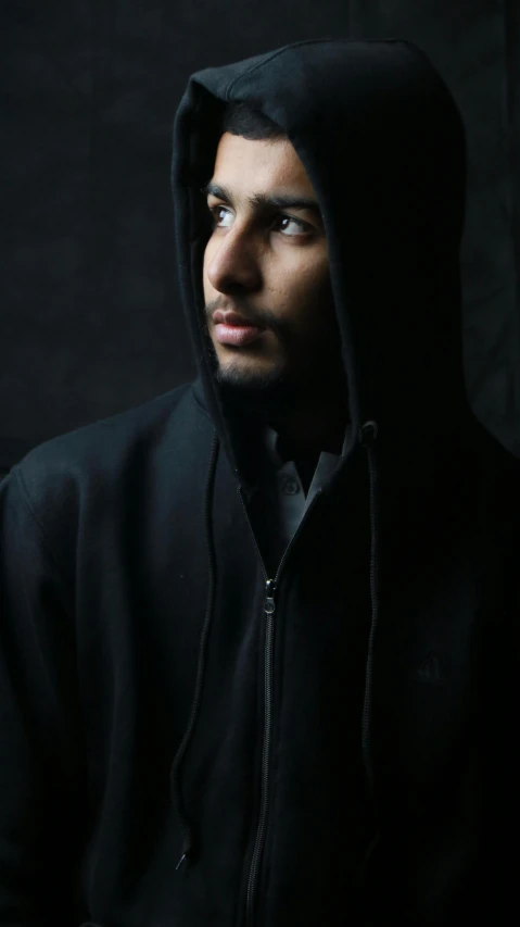 a man in black standing by a black backdrop