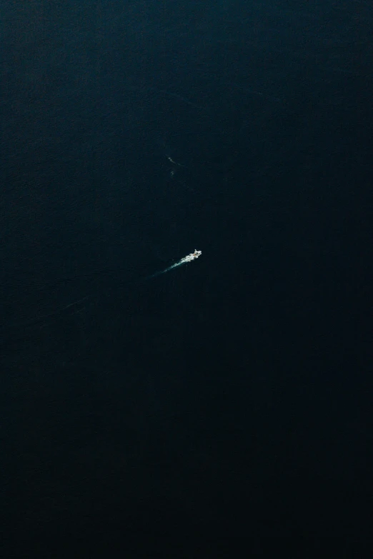 a airplane flying over a boat in the ocean at night
