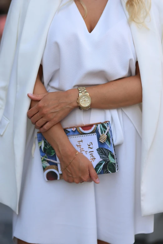 a close up of a person wearing white and holding a wrist watch