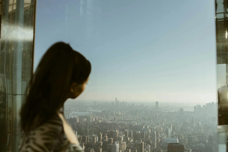 a woman looking out the window at a large city