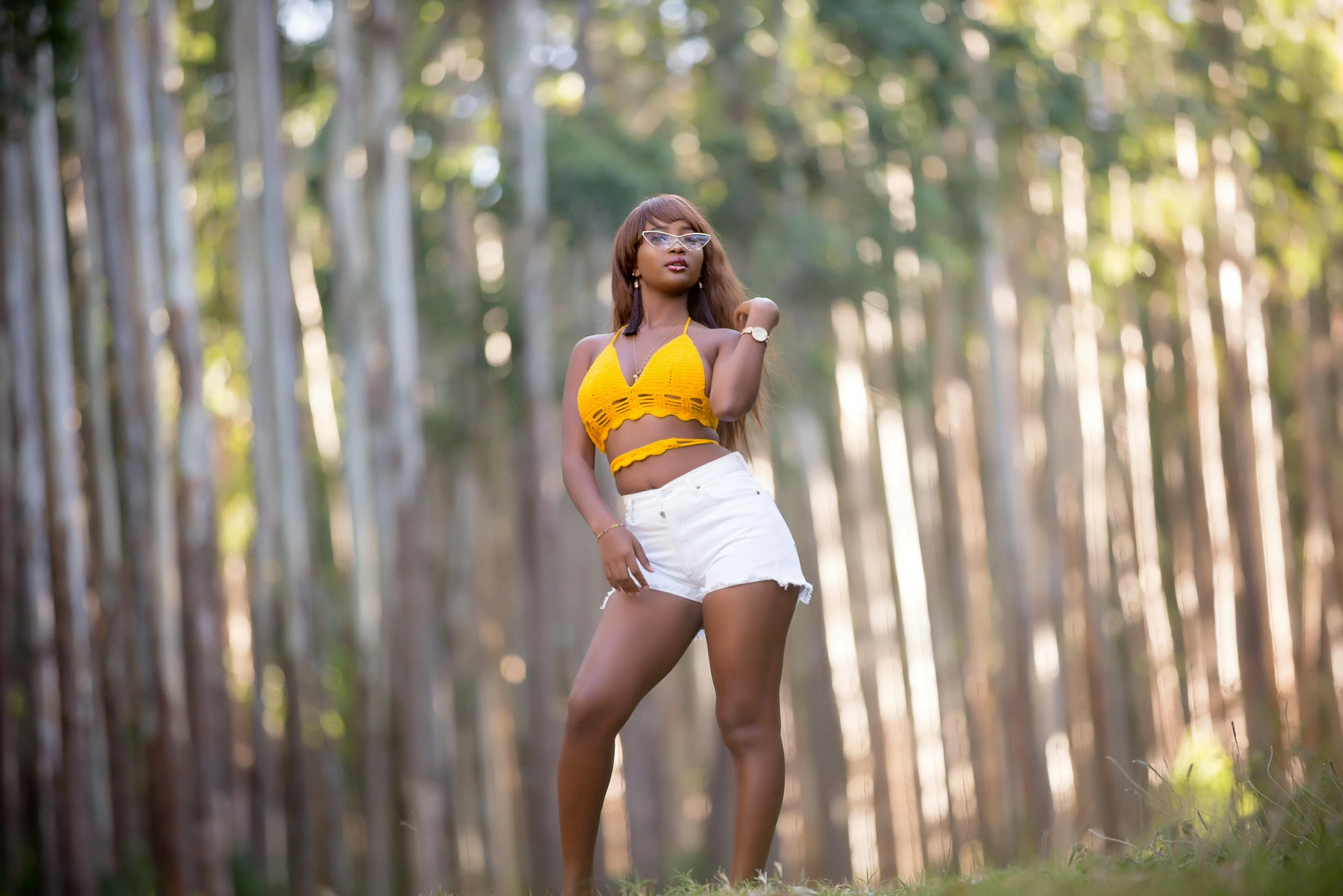 a young woman is posing in front of tall trees