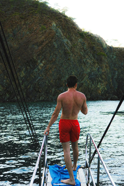 a man walks on the front of a sailboat through the water