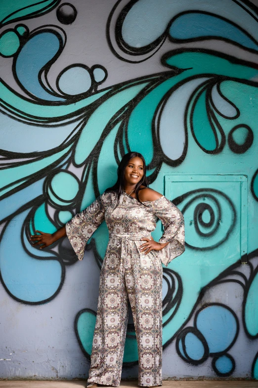 a woman stands in front of a graffiti covered wall