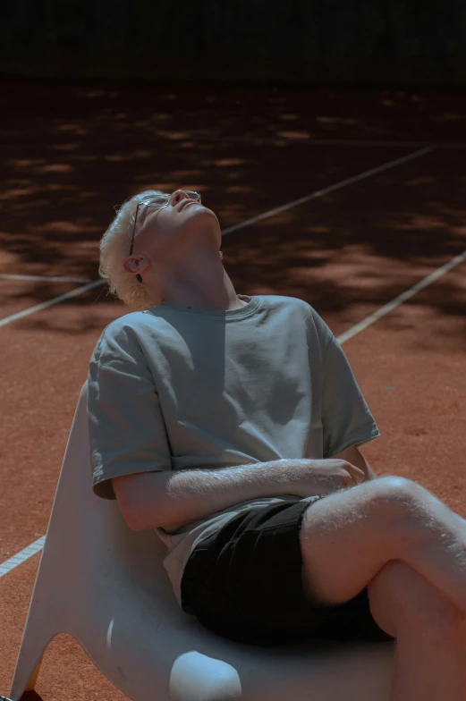 an older man laying on a chair next to the tennis court