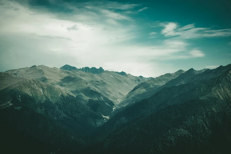 mountains are surrounded by cloudy skies and trees