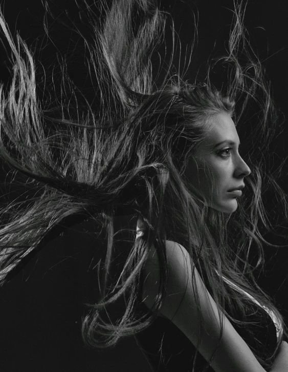 a woman is blowing her hair with a black background