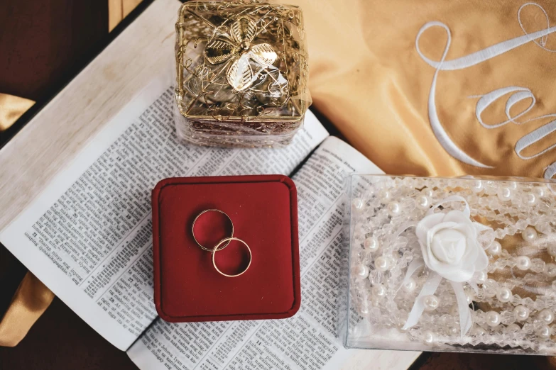 two open rings are in an empty red box, next to an open white rose