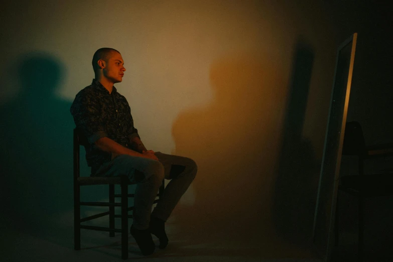 a man sits in a chair and is lit by a small lamp