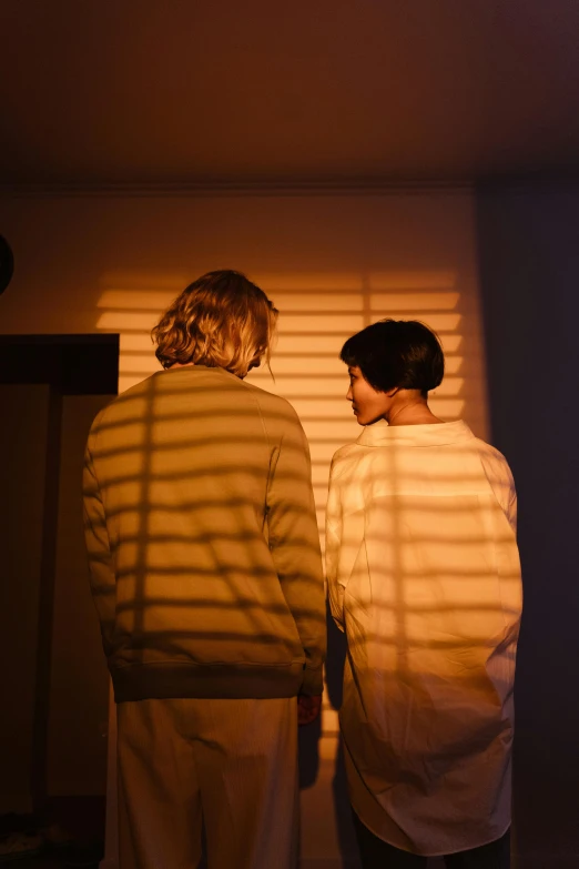 two men look at the blinds on a wall