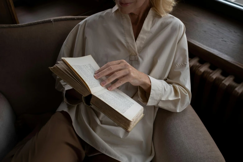 a woman sits on a couch reading a book