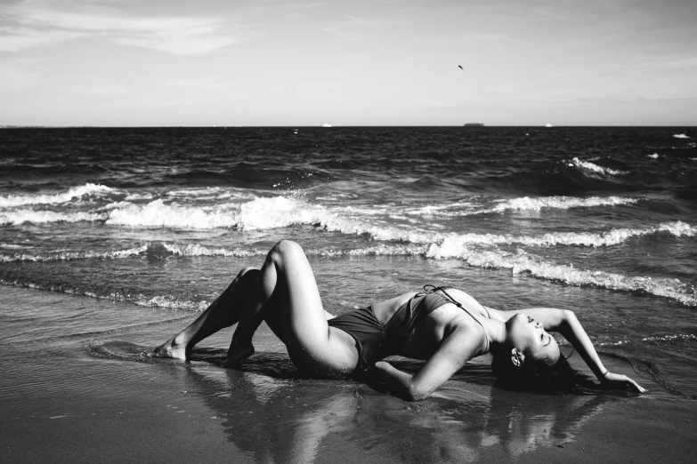 a woman laying in the sand near water