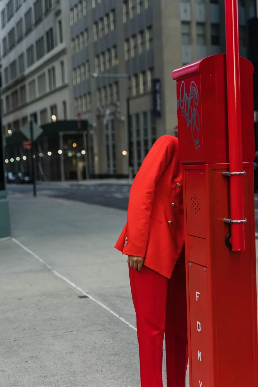 a man in a red suit standing by the red fire hydrant