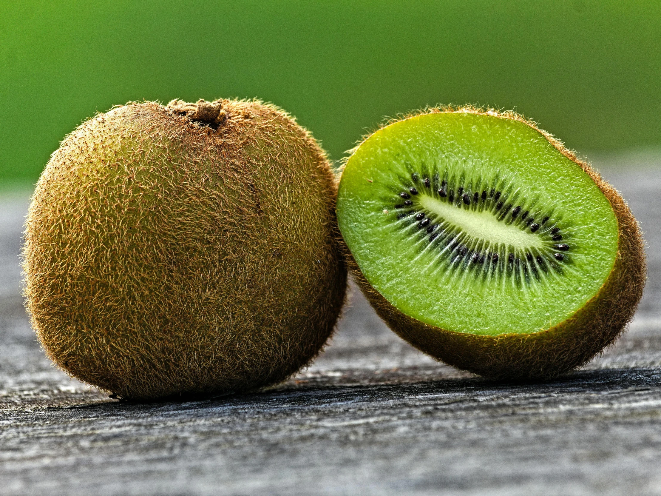 a kiwi cut in half on a wood table