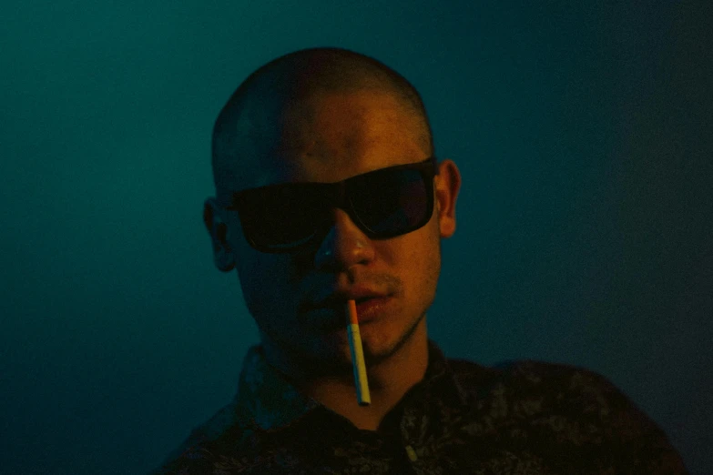 man in sunglasses smoking and holding cigarette in mouth