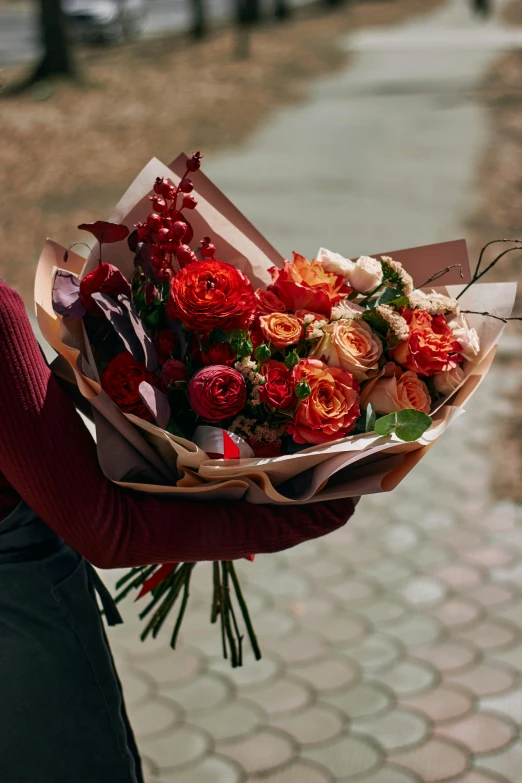 a person holding a bouquet of flowers outdoors