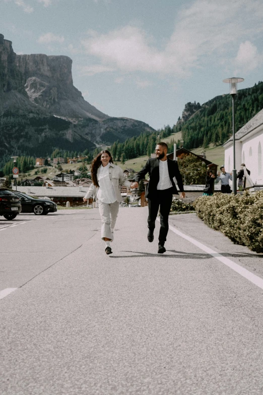 a couple is walking down a street with a mountain behind them