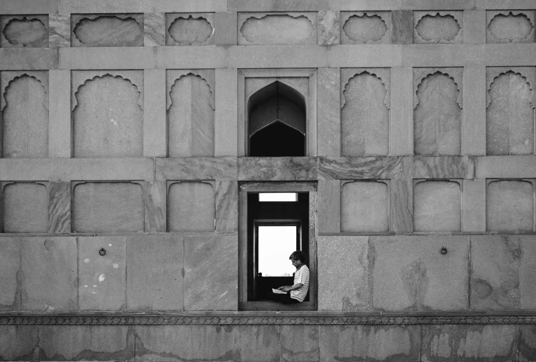 black and white pograph of person looking out window