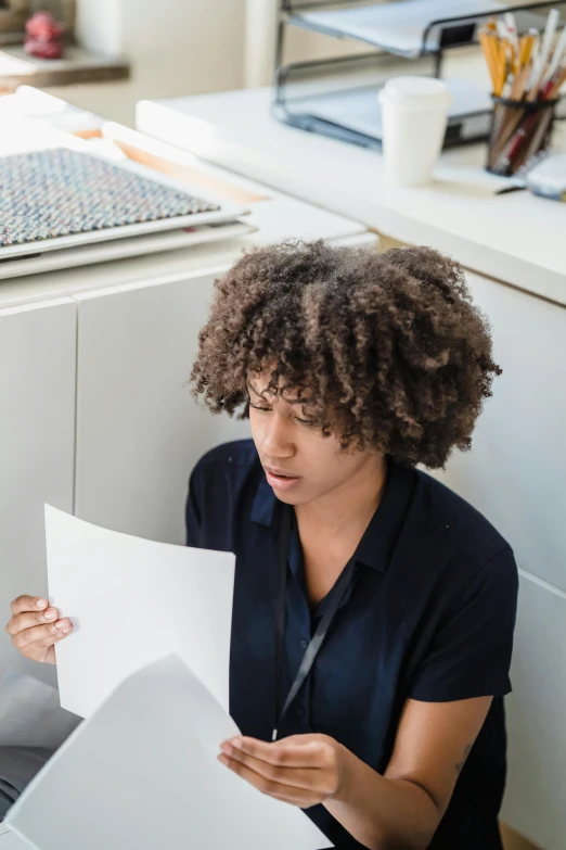 a woman reading soing at the desk with a black shirt on