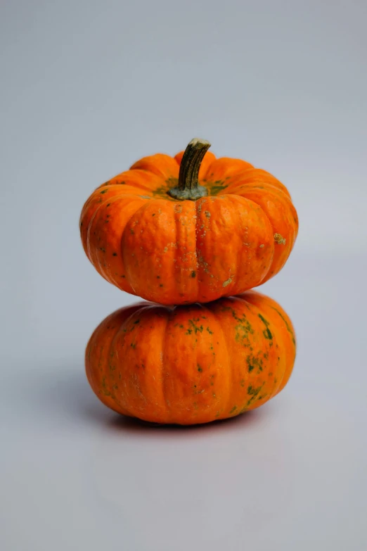 two small orange pumpkins sitting on top of each other