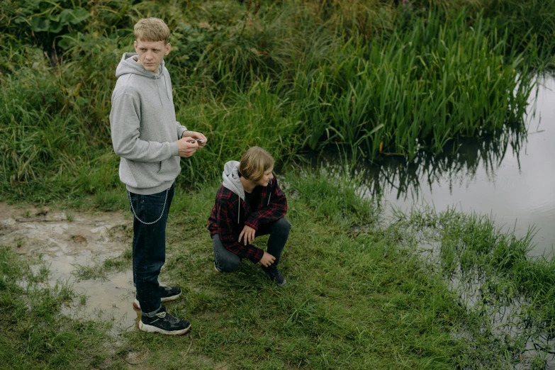 two people stand on the shore in front of a body of water