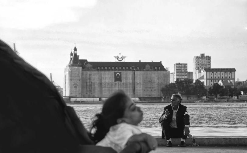 a woman sits on a park bench as a child walks past