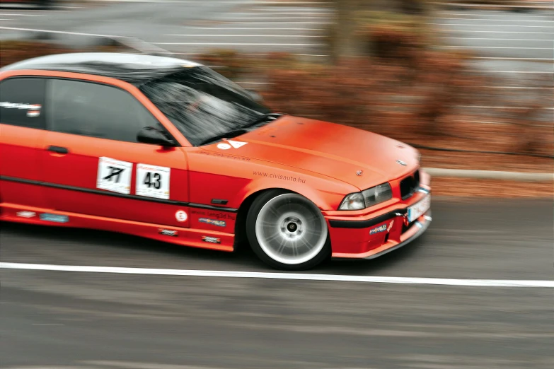 a red and white bmw car traveling down the road