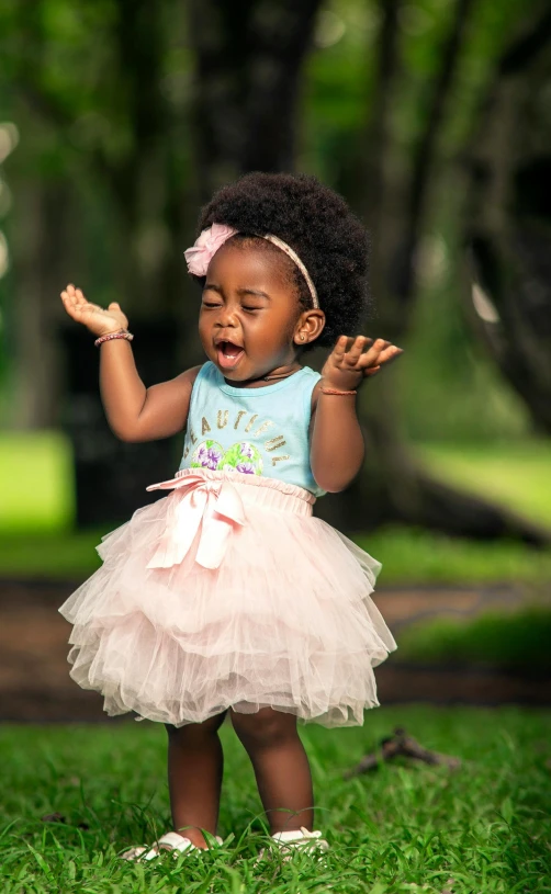 a baby girl with an afro is on the grass and screaming