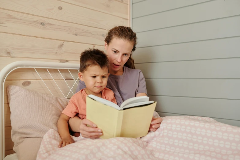 a woman reads a book to a child on her bed