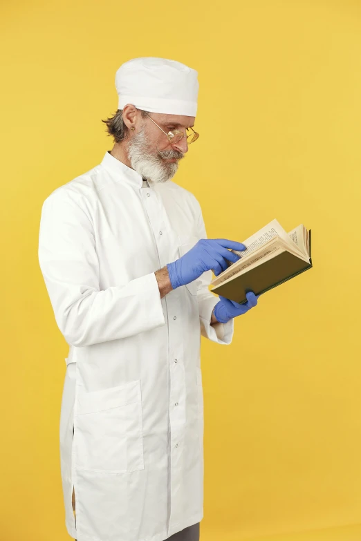 an indian man reading a book in front of a yellow background