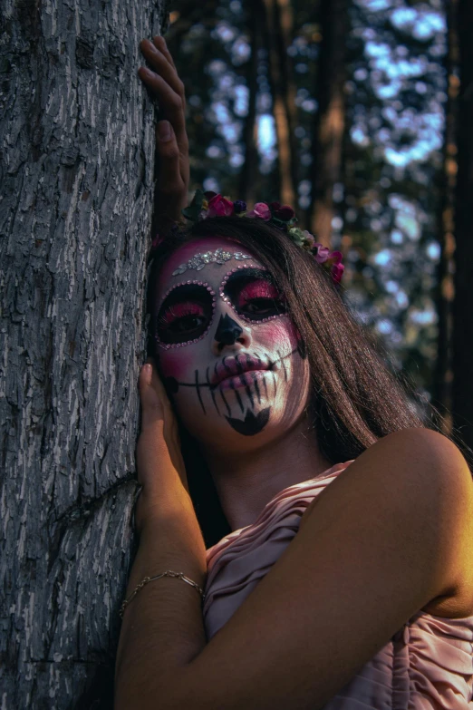 a girl with skeleton makeup on stands next to a tree