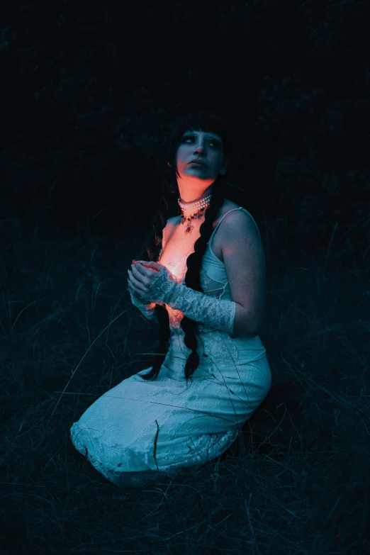 a girl sitting on the ground at night