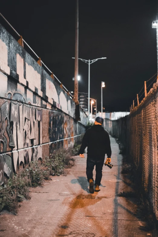 man walking down a small city street at night