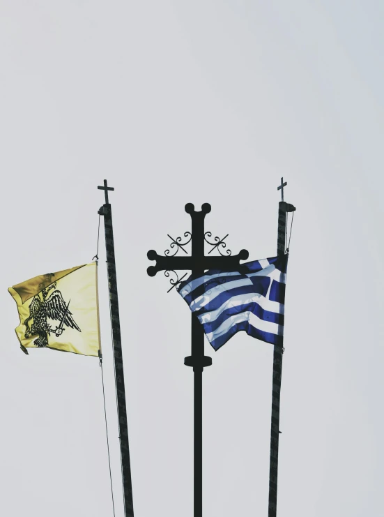 a cross, an american flag and a greek flag fly in the sky