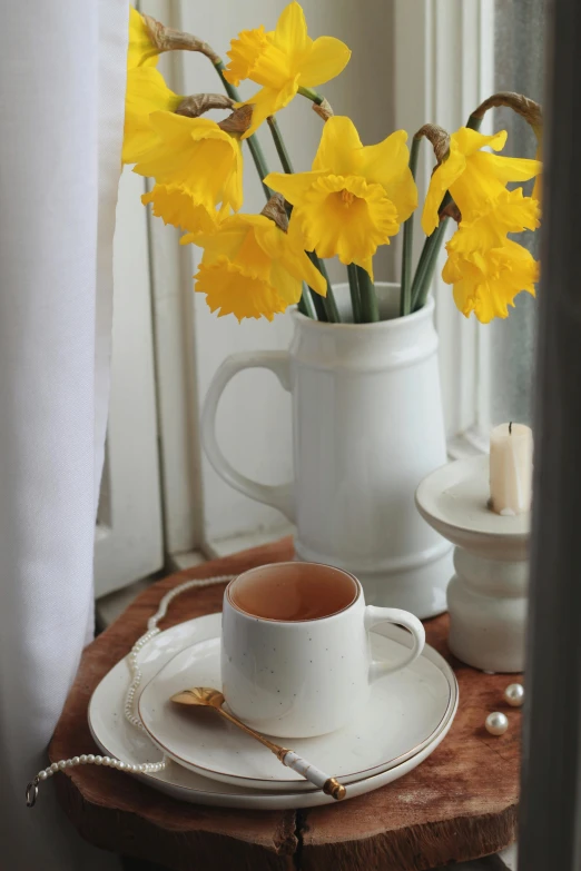 a bouquet of daffodils sits in a white cup on a white plate