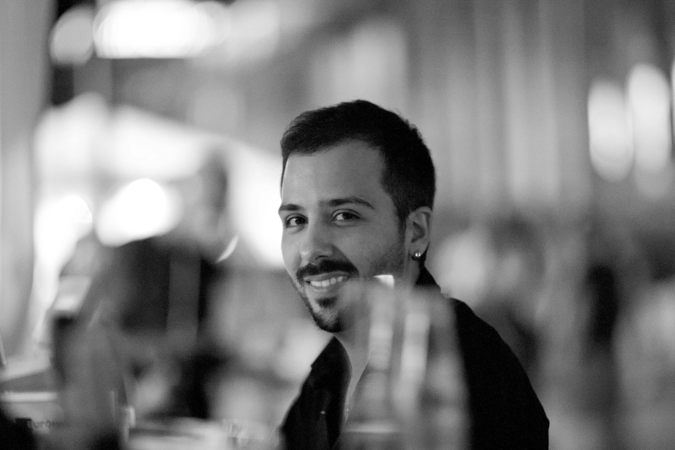 a man sitting down at a table with wine glasses