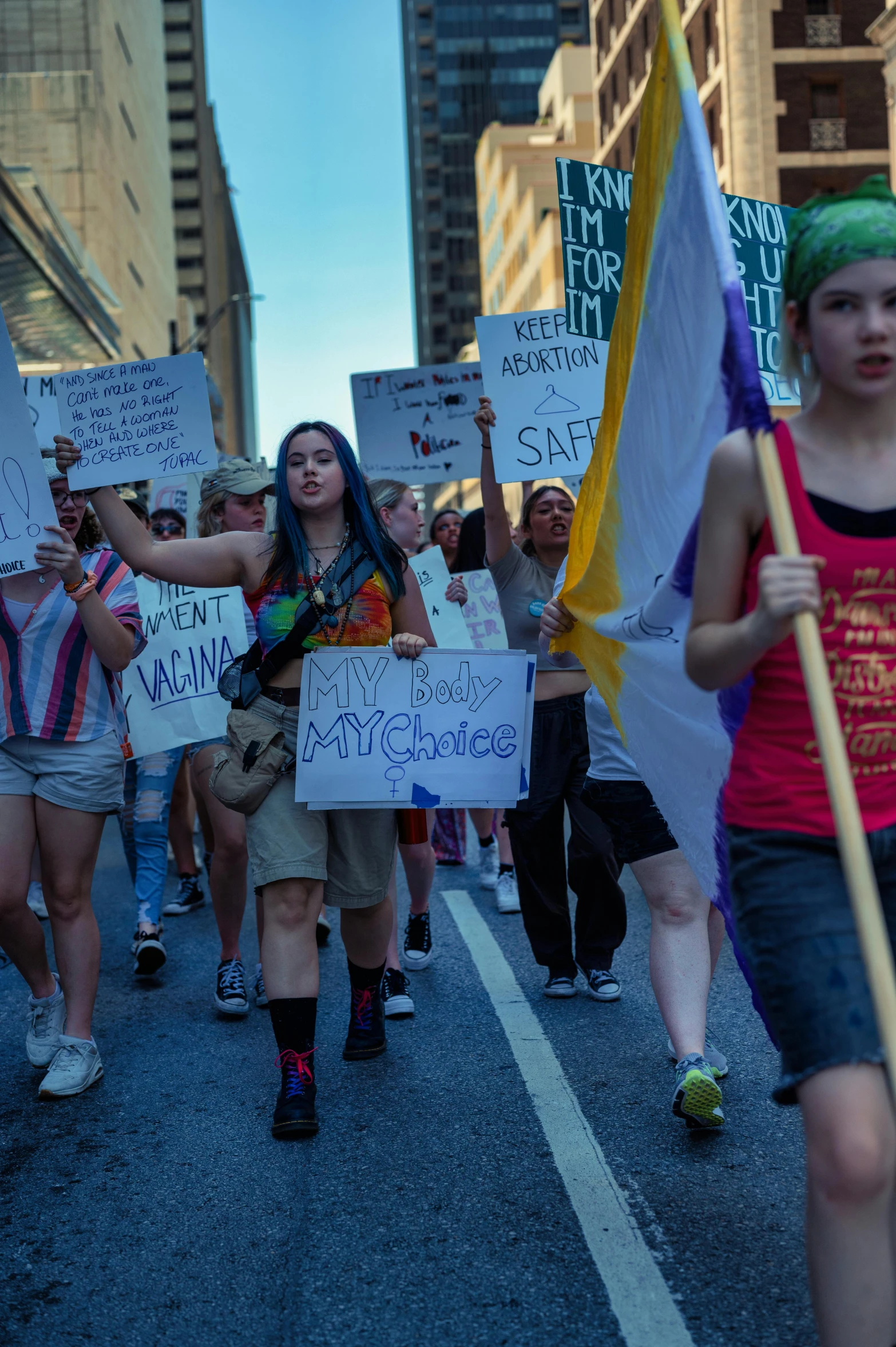 many people walking down the street with signs