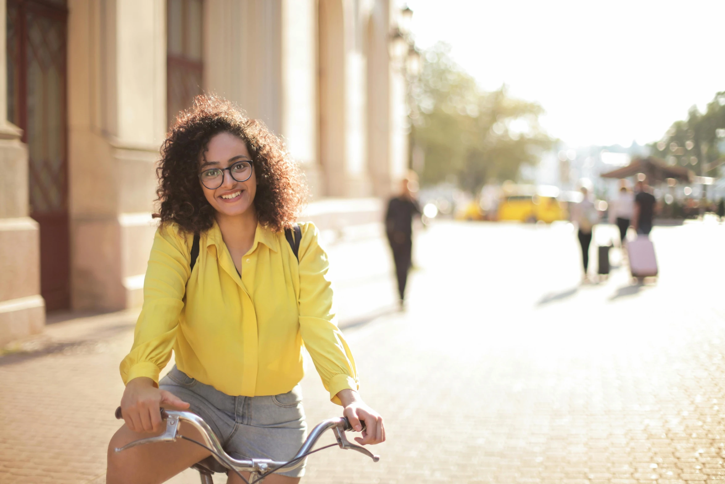 a smiling woman rides her bicycle down the street