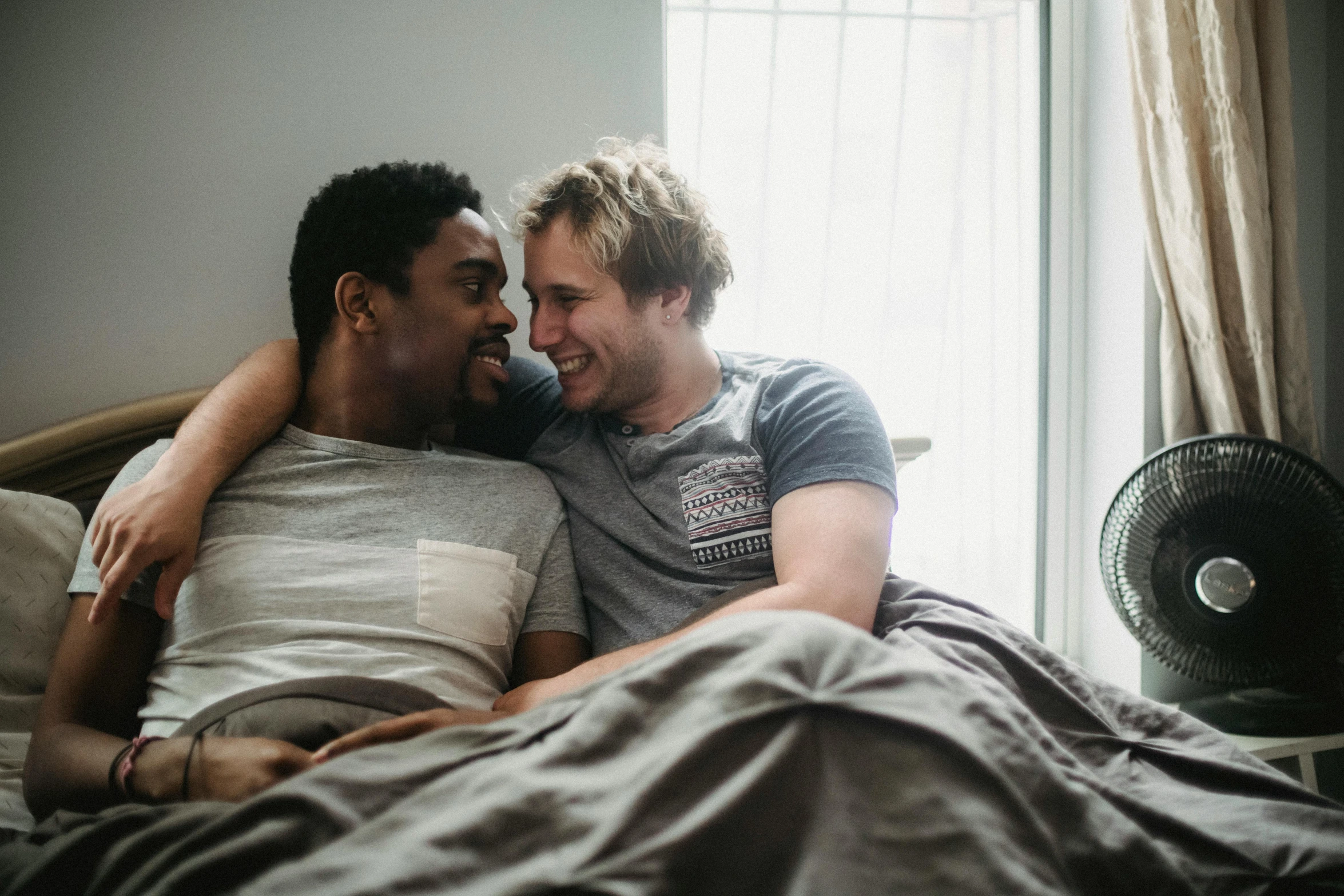 two men hugging each other in a bed