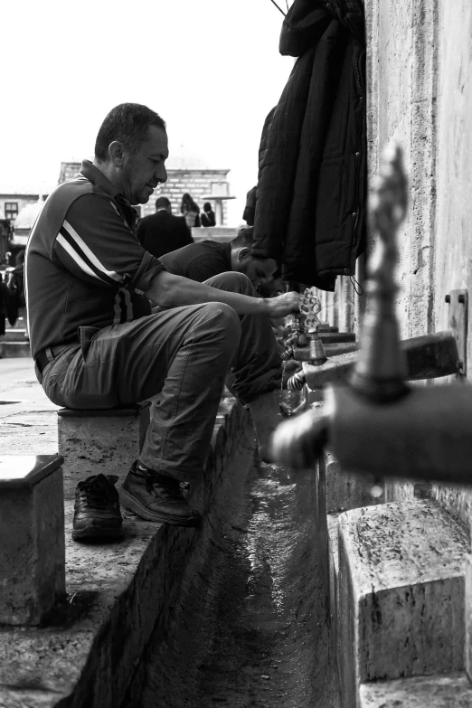 man sitting on concrete block in the rain