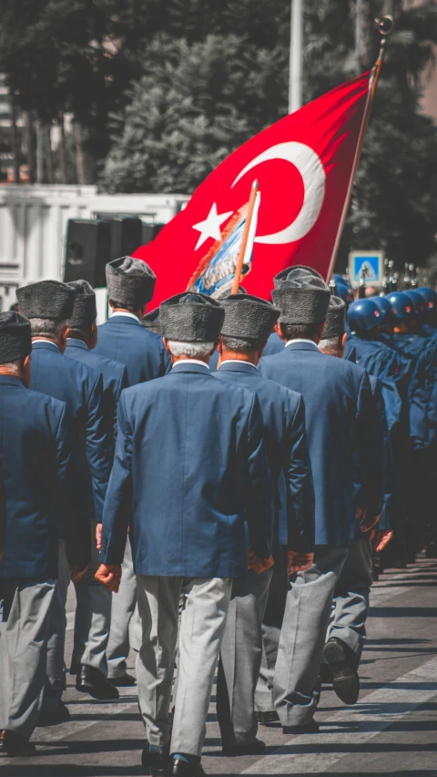 the men are marching while carrying a large turkey flag