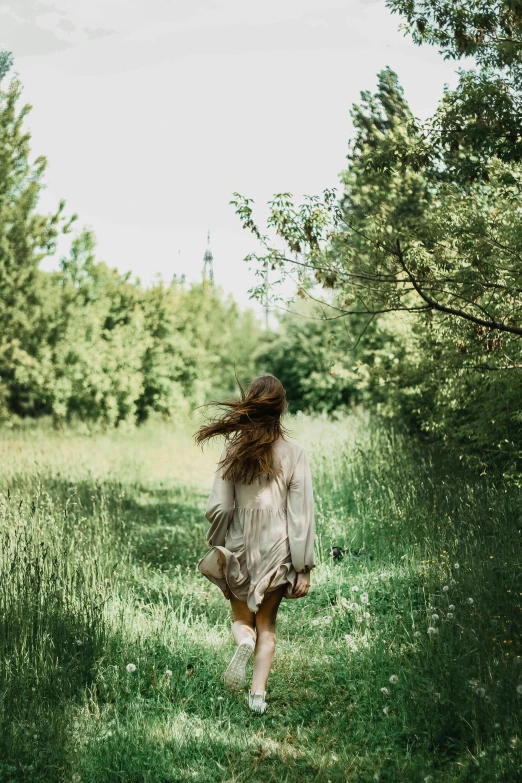 a young woman walking through a green field