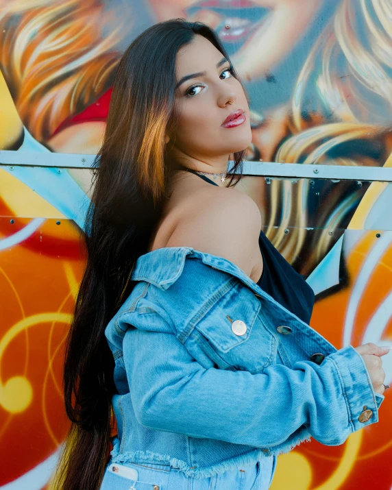 a beautiful young woman in denim standing in front of a graffiti wall