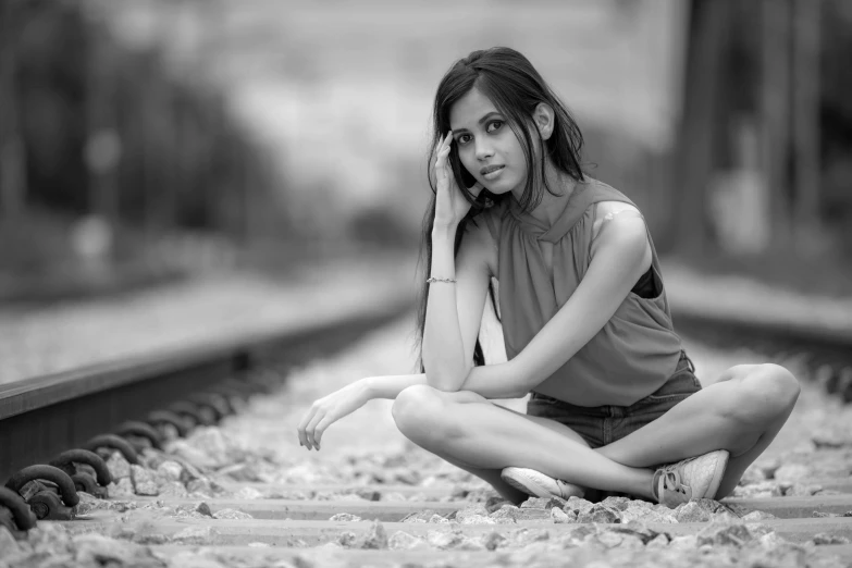 a woman sitting on the train tracks with her hands on her head