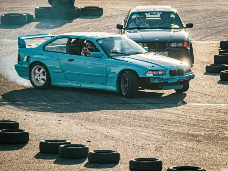 a blue car drives past some tires on the road