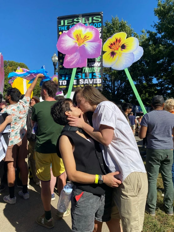 a couple is kissing each other with the festival sign behind them