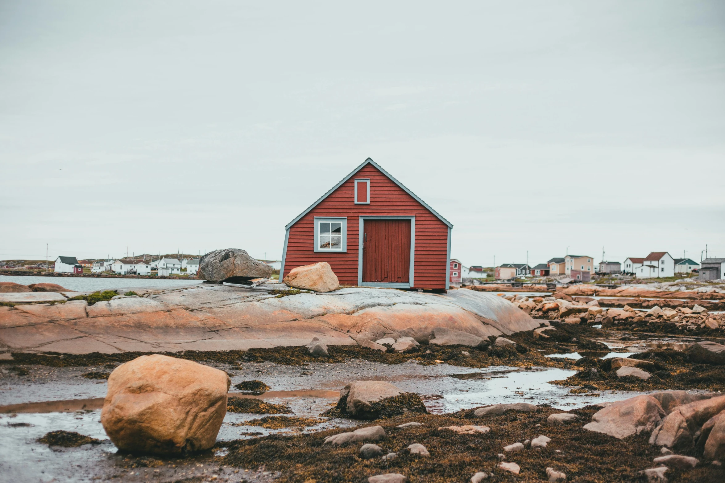 a red house on some rocks and water