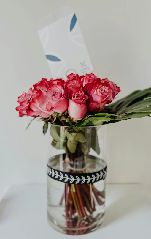 a clear vase holding some red roses in water