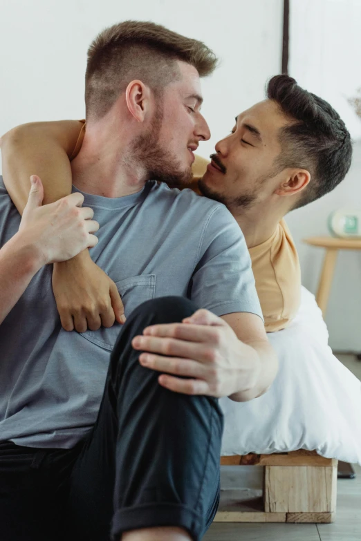 a man holding a young man while sitting on the floor