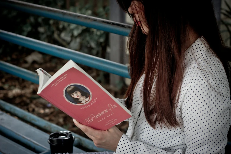 a woman reading a book with a drink on her lap