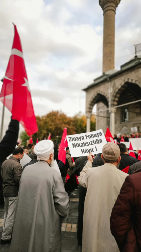 many people with red and white signs are standing